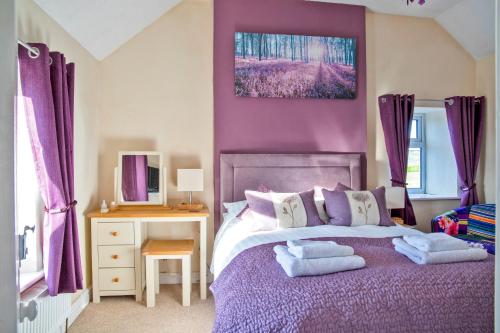 Moorland View Farm B&B في Oakamoor: غرفة نوم أرجوانية مع سرير عليه مناشف
