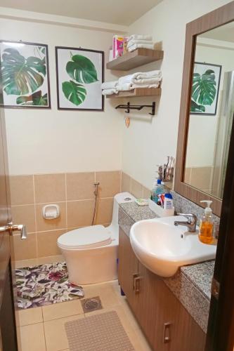 a bathroom with a toilet and a sink and a mirror at Joey's Place Calathea DMCI in Manila