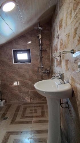 a bathroom with a sink and a tv on the wall at Agro House Mezge - აგროსახლი მეზგე in Bashkʼo