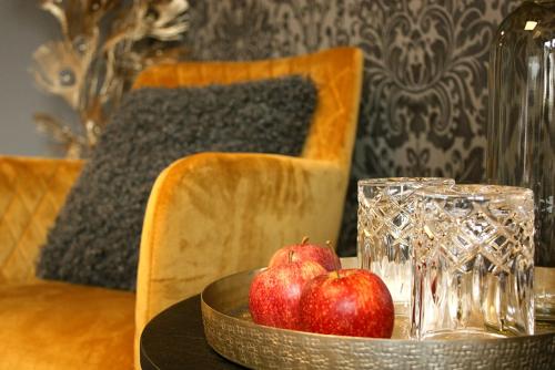 two apples in a bowl on a table with glasses at Boutique-Pension Jägerwirt in Scheffau am Wilden Kaiser