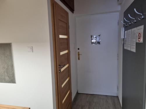a hallway with a wooden door and a white wall at Downtown Studio Apartman in Pécs