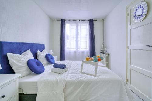 a white bed with blue pillows and a table on it at My Cosy Home 1 in Vitry-sur-Seine