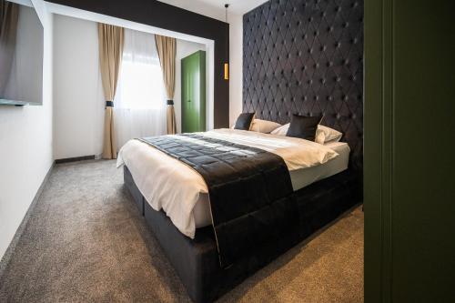 a bedroom with a large bed with a black headboard at DMS Apartments & Suites Sarajevo in Vogošća