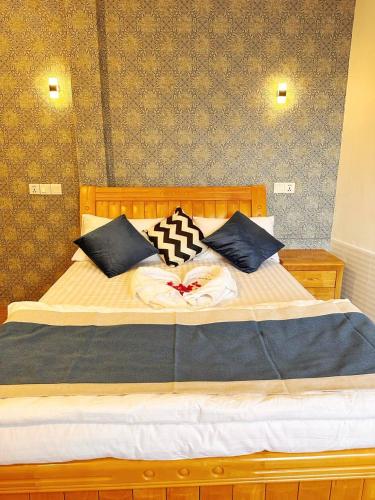 a wooden bed with black and white pillows on it at Aqua Sunset in Gulhi