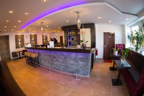 a bar in a restaurant with purple lighting at Boutique Hotel Goldene Henne in Wolfsburg