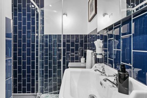 a bathroom with a sink and a blue tiled wall at The Somerville in Torquay