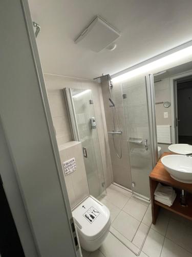 uma casa de banho com um WC, um chuveiro e um lavatório. em Hotel16 by Messe & Stadion Suisse in Minuten & Late Check-in em Berna