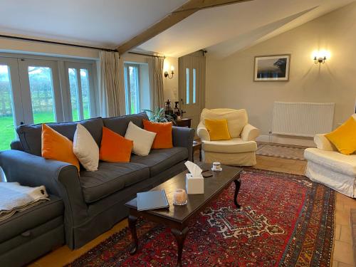 Baltonsborough的住宿－The Long Barn，客厅配有蓝色沙发和橙色枕头。