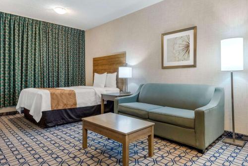 a hotel room with a bed and a couch and a chair at Quality Suites in Whitby
