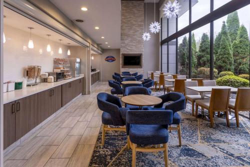 a waiting area with tables and chairs in a lobby at Baymont by Wyndham White Plains - Elmsford in Elmsford