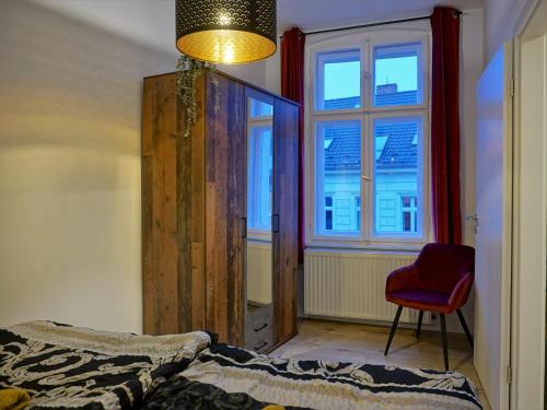 ein Schlafzimmer mit einem Bett, einem roten Stuhl und einem Fenster in der Unterkunft "HOGULU" Brandenurg Neustadt, Balkon, Küche, Wassernähe in Brandenburg an der Havel