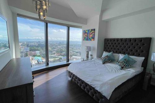 a bedroom with a bed and large windows at AEON Towers Davao in Davao City