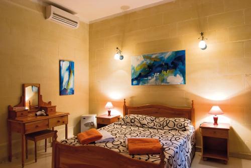 een slaapkamer met een bed en een bureau met 2 lampen bij Djar Ta Menzja 3 Holiday Home in Sannat