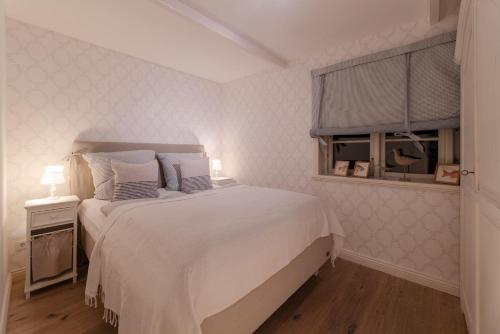 a bedroom with a white bed and a window at von-Deska-Countryhouses-Offiziers-Apartment in Nieblum