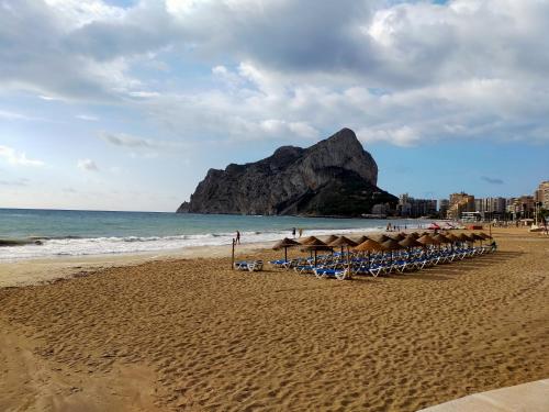 una spiaggia con sedie e ombrelloni e l'oceano di EL DESCANSO a Calpe