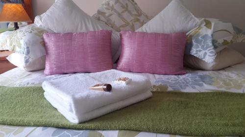 a bed with white towels and pink and purple pillows at Harmony Guesthouse in Nelspruit