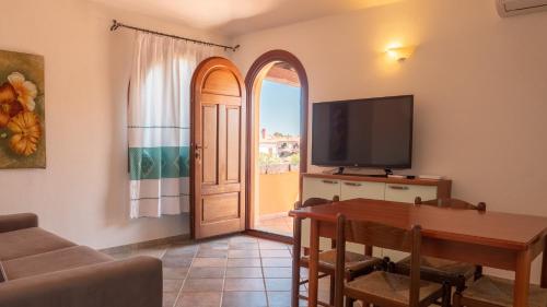 sala de estar con mesa, TV y puerta en Casa Vacanza la Suaredda, en San Teodoro