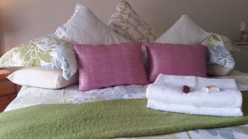 a bed with several pillows and a towel on it at Harmony Guesthouse in Nelspruit