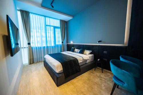 a bedroom with a bed and a blue wall at DMS Apartments & Suites Sarajevo in Vogošća
