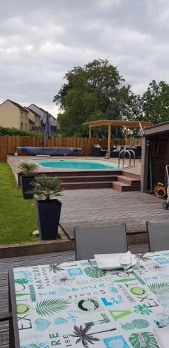 un patio avec une table et des chaises et une piscine dans l'établissement Location 24 heures du Mans auto, à Parigné-lʼÉvêque