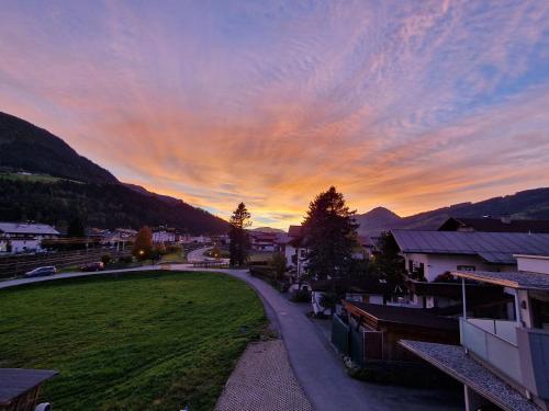 einen Sonnenuntergang über einer Stadt mit einem grünen Feld in der Unterkunft Appartement Lurger in Kirchberg in Tirol