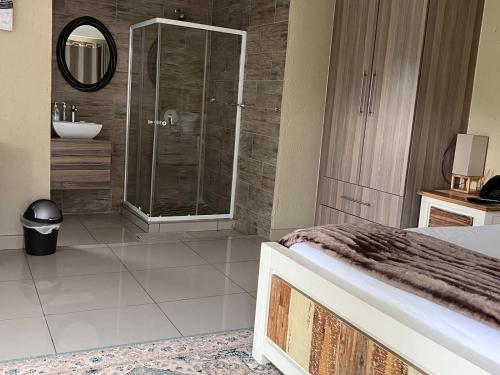 a bathroom with a shower and a bed and a sink at THE BRIDGE BOUTIQUE LODGE in Moletlane