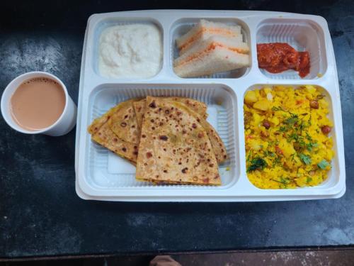 een lunchbox met wat eten en een kopje koffie bij Wotel Calangute Goa in Calangute