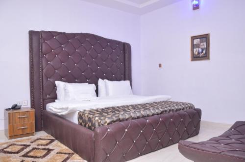 a bed with a padded headboard in a room at Akure Airport Hotel in Oba Ile