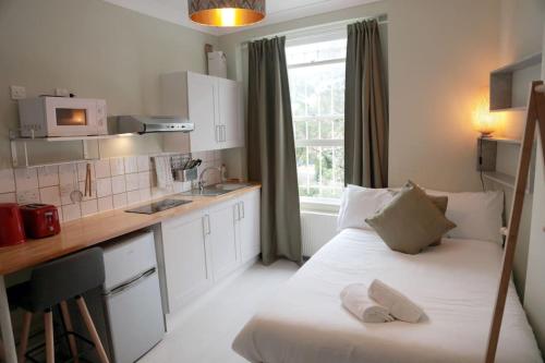 een kleine kamer met een bed en een keuken bij Cosy Chic Studio in King's Cross in Londen