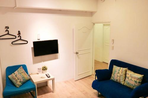 Una sala de estar con dos sillas azules y un televisor. en 心旅地圖青年旅館, en Changhua City