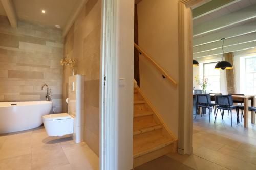 a bathroom with a bath tub and a staircase at Hoogheem Erfgoed & Logies in Nieuwolda