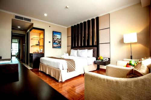 a hotel room with two beds and a couch at Ros-In Hotel in Yogyakarta