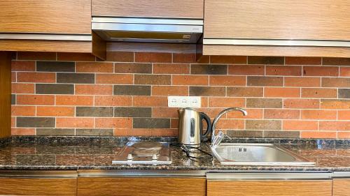 a kitchen counter with a sink and a brick wall at Новая квартира у Площади in Yerevan