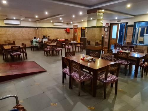 a restaurant with tables and chairs and people in the background at Hotel MGM Grand in Srikalahasti