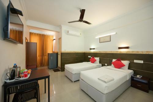 a hotel room with two beds and a television at Nettoor Pavilion in kumbalam