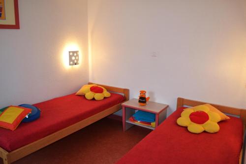 - une chambre avec 2 lits dotés de draps rouges et d'une couverture rouge dans l'établissement VVF Jura Lac de Vouglans, à Maisod