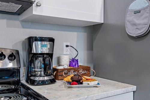 a kitchen counter with a coffee maker and a plate of food at Welcome to Cozy Coastal Cottages of Dunedin #1 in Dunedin