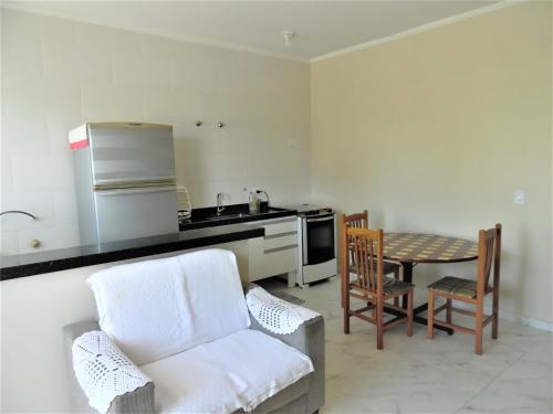 a kitchen with a couch and a table and a kitchen with a stove at Apto Aluguel na Temporada Pé na Areia Peruíbe SP in Peruíbe
