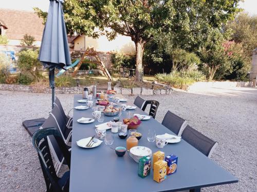 een blauwe tafel met eten en een parasol bij Au pays de Jacquou : Chambre d’hôtes et table d’hôtes in Fossemagne