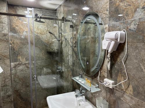 a bathroom with a shower and a sink and a mirror at Rayyan Hotel Samarkand in Samarkand
