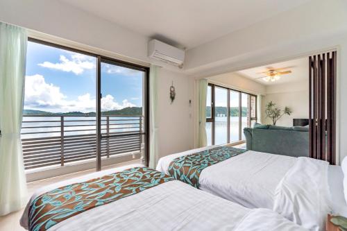 2 Betten in einem Zimmer mit einem großen Fenster in der Unterkunft Lala court seaside Yagaji / Vacation STAY 3226 in Nago