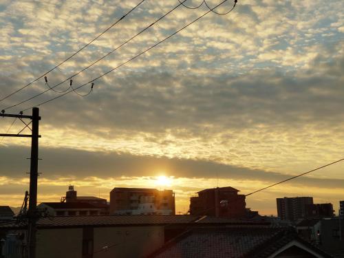 uma vista para o pôr do sol a partir do telhado de uma cidade em OTERA HOUSE 瑞　TAMA em Osaka
