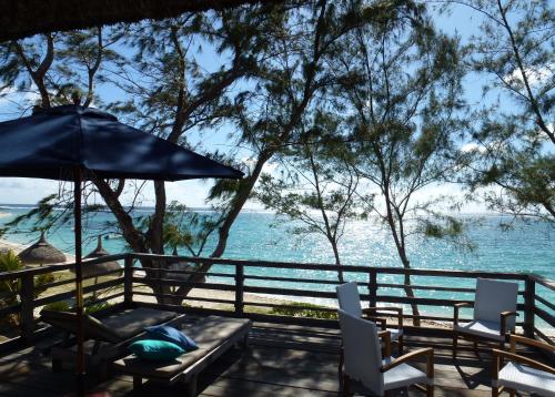 a table and chairs with an umbrella and the ocean at BlueMoon Villa - Authentic, seaside living in Trou dʼ Eau Douce