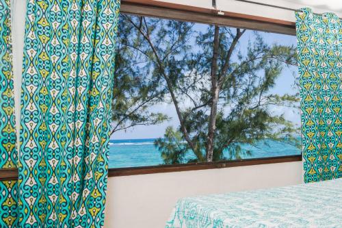 a bedroom with a window with a view of the ocean at BlueMoon Villa - Authentic, seaside living in Trou dʼ Eau Douce
