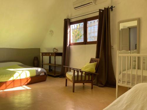ein Schlafzimmer mit einem Bett, einem Stuhl und einem Fenster in der Unterkunft BlueMoon Villa on The Beach in Trou dʼ Eau Douce