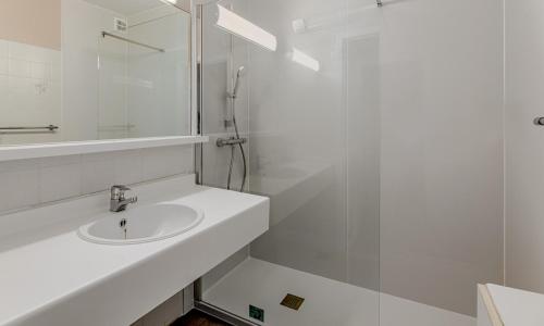 uma casa de banho branca com um lavatório e um chuveiro em Korre 0302 em Koksijde