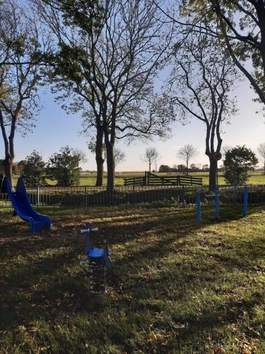 a playground with a slide in a park with trees at De Oude Pastorie in Bunschoten