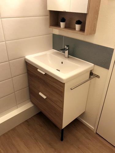 La salle de bains est pourvue d'un lavabo blanc. dans l'établissement Appartement 4 pers Tour de la Biche skis aux pieds, à Besse-et-Saint-Anastaise