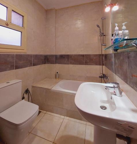 a bathroom with a sink and a toilet and a tub at Modern entire apartment in the heart of Sheikh Zayed city in Sheikh Zayed