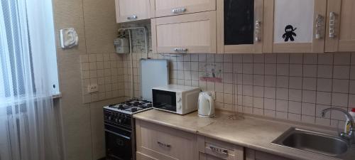 eine Küche mit einem Herd und einer Mikrowelle in der Unterkunft 1к квартира Антоновича. Олімпійська in Kiew